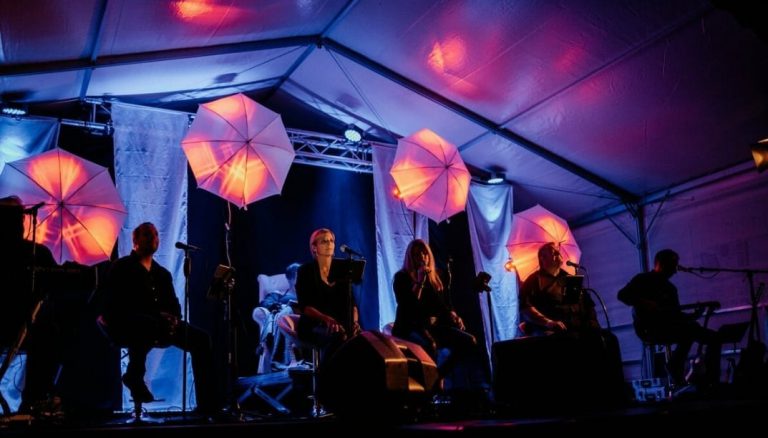 Musiker auf einer Bühne unter stimmungsvoll beleuchteten Schirmlampen bei einer Gala-Veranstaltung