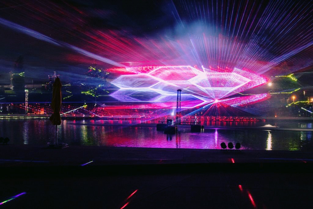 Lasershow mit synchronisierten Laserformationen über dem Wasser bei Nacht